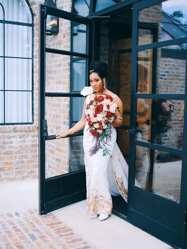 Bride in an ivory gown with gold leaf appliqué in a doorway
