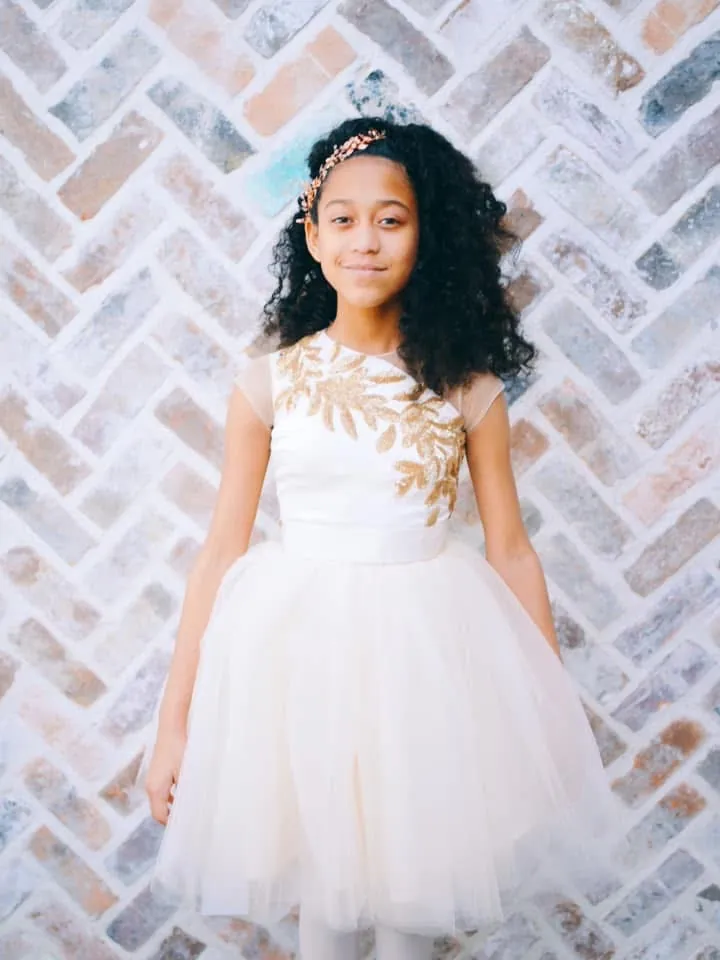 Girl in an ivory tulle dress with a gold-embroidered bodice