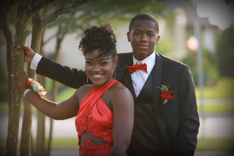 Prom couple in a coordinated red gown and black tuxedo