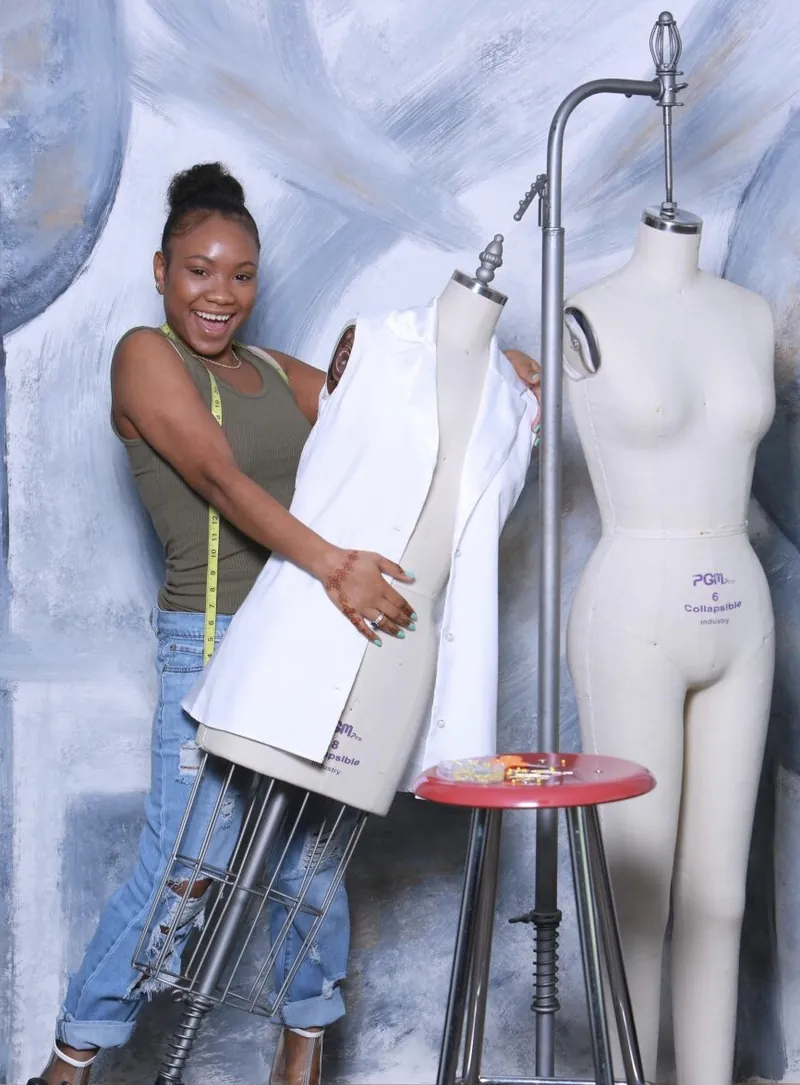 Shelena pinning an ivory garment on a dress form